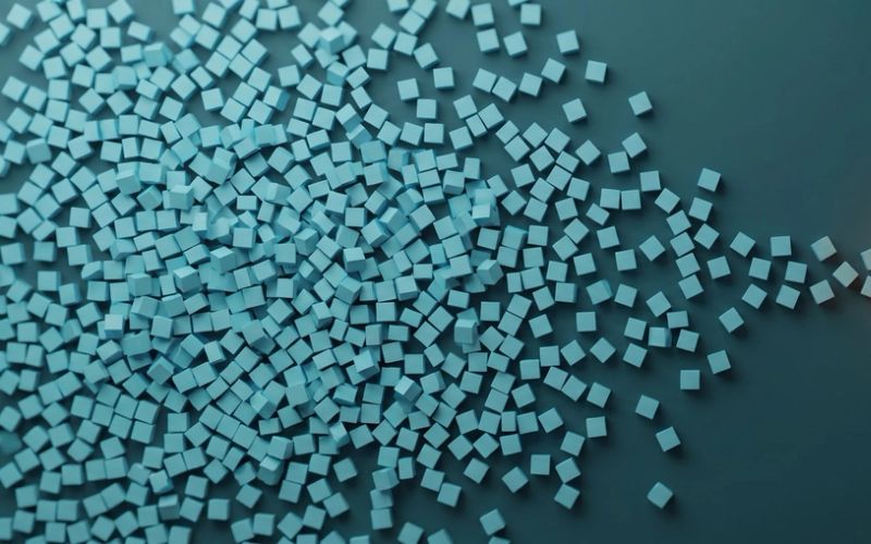 A wide sprawl of loose pale cubes resolving on the right into one tidy amber-lit cluster of four
