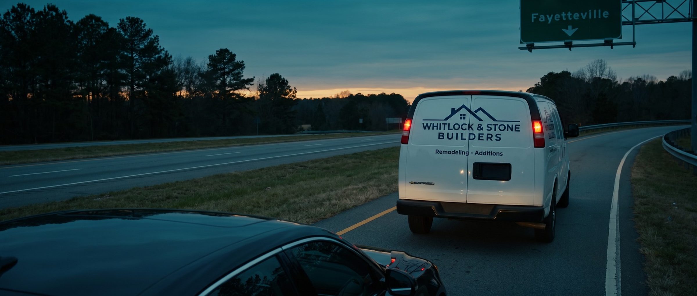 A remodeling company's lettered white cargo van merging onto a highway at dusk under an overhead exit sign for Fayetteville