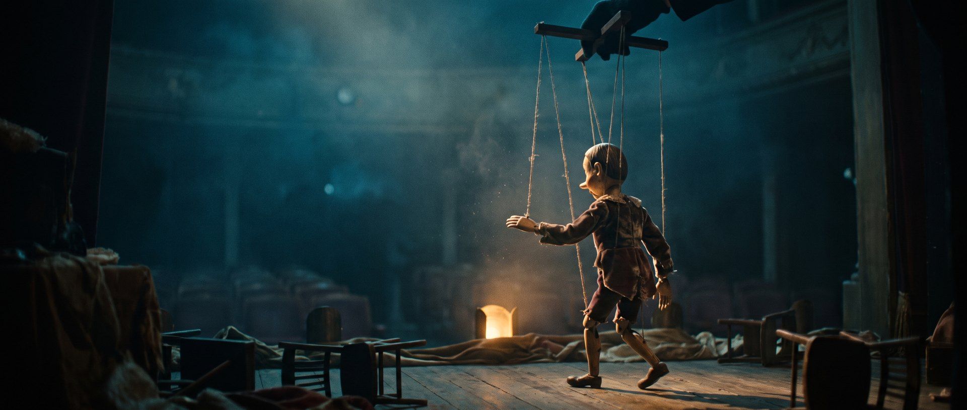 A wooden marionette performing on a dim stage, its strings running up to an unseen hand above
