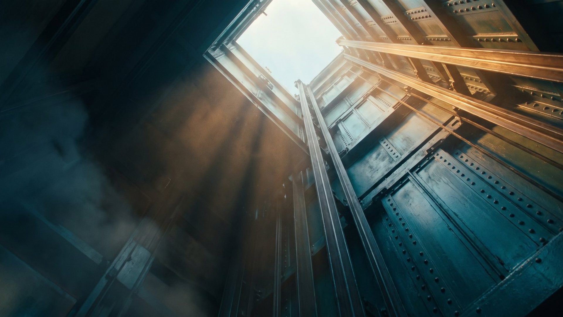 Looking straight up a deep industrial lift shaft that opens into bare sky at the top, with nothing capping it