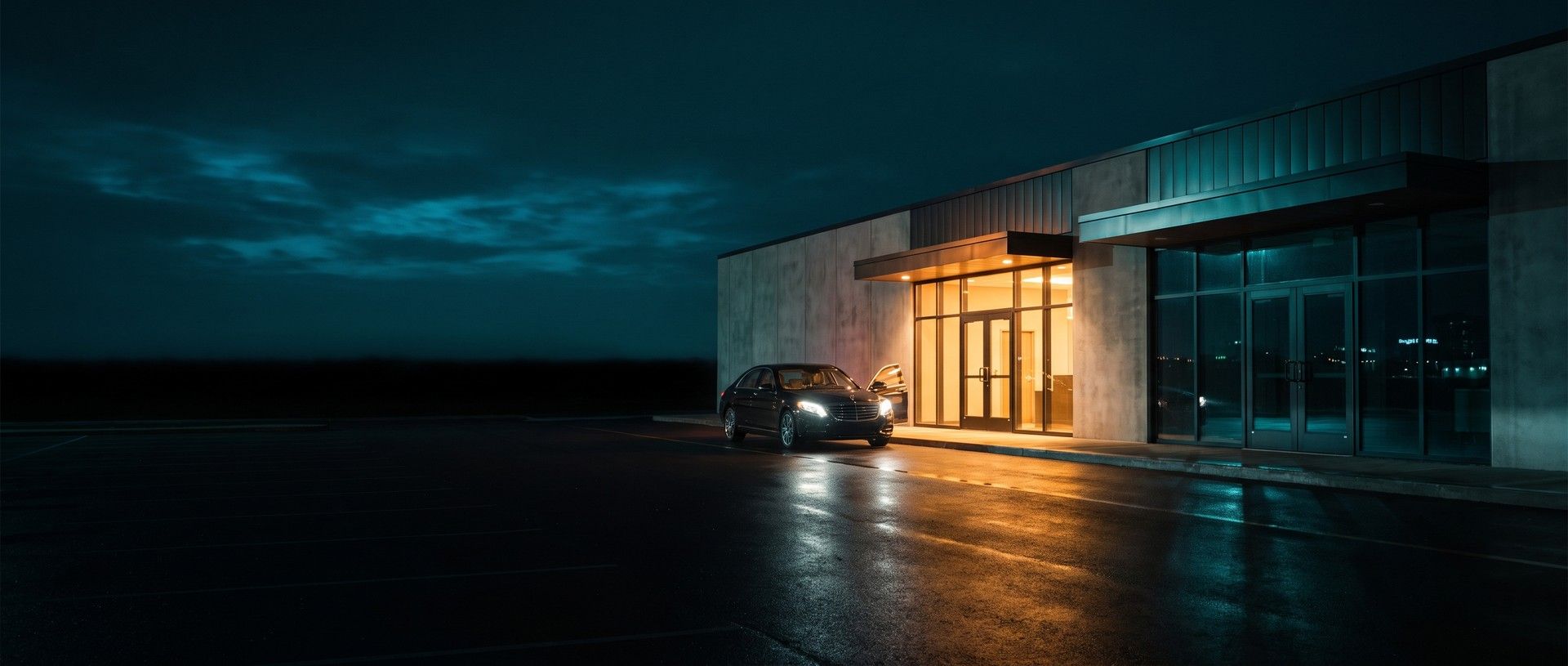 A veterinary hospital at night with two entrances: one lit amber with a car pulled up, headlights on and door open, the other dark and closed for the night