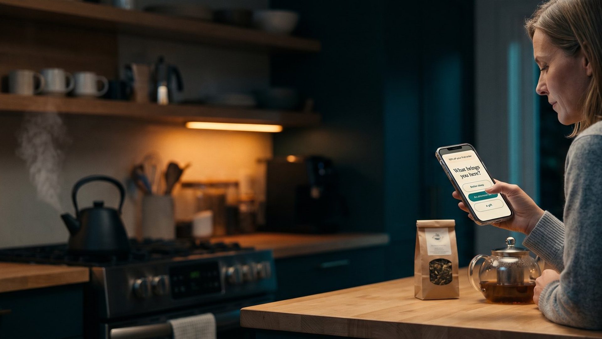 A woman at her kitchen counter in the evening holds her phone, where an online tea shop's signup popup asks What brings you here? with three answer buttons: Better sleep, An afternoon lift, and A gift, while a kettle steams on the stove behind her