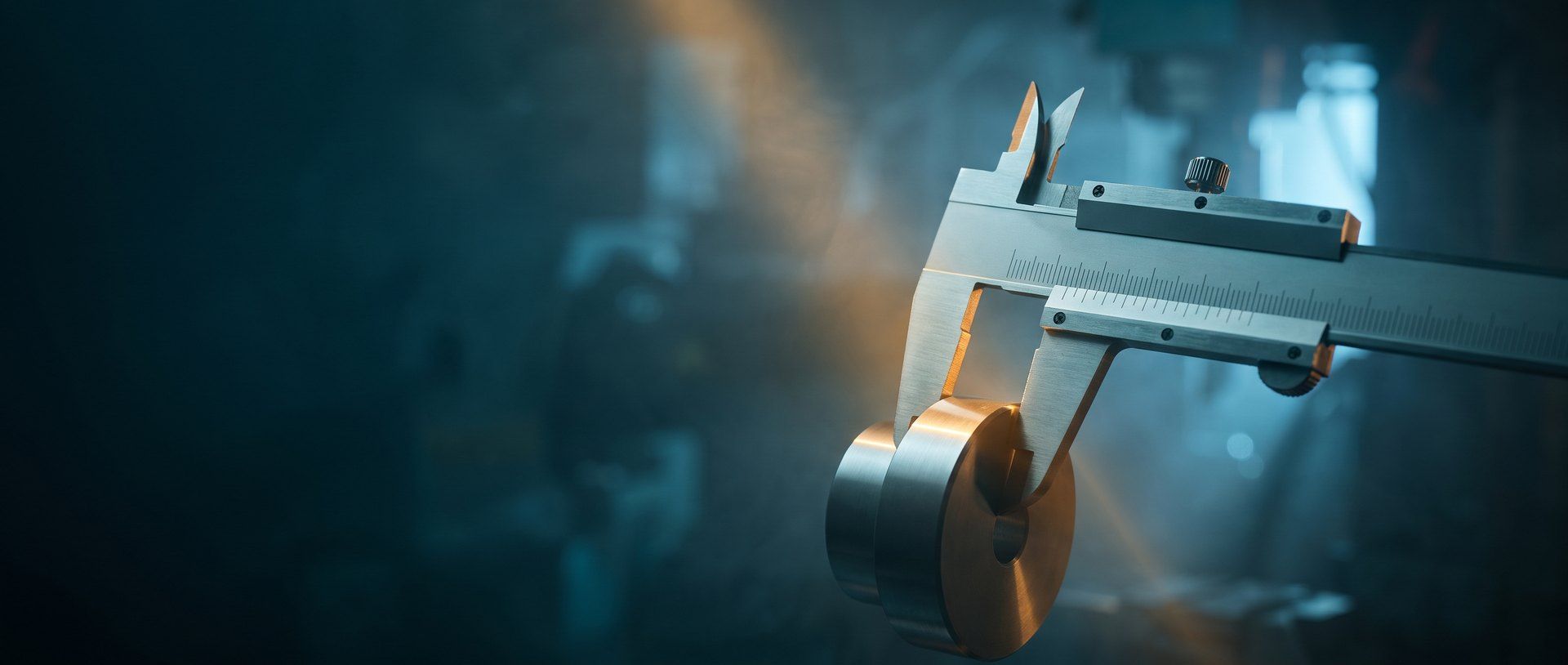 A steel vernier caliper closing on a machined metal part, warm amber light raking across it in a dim teal workshop