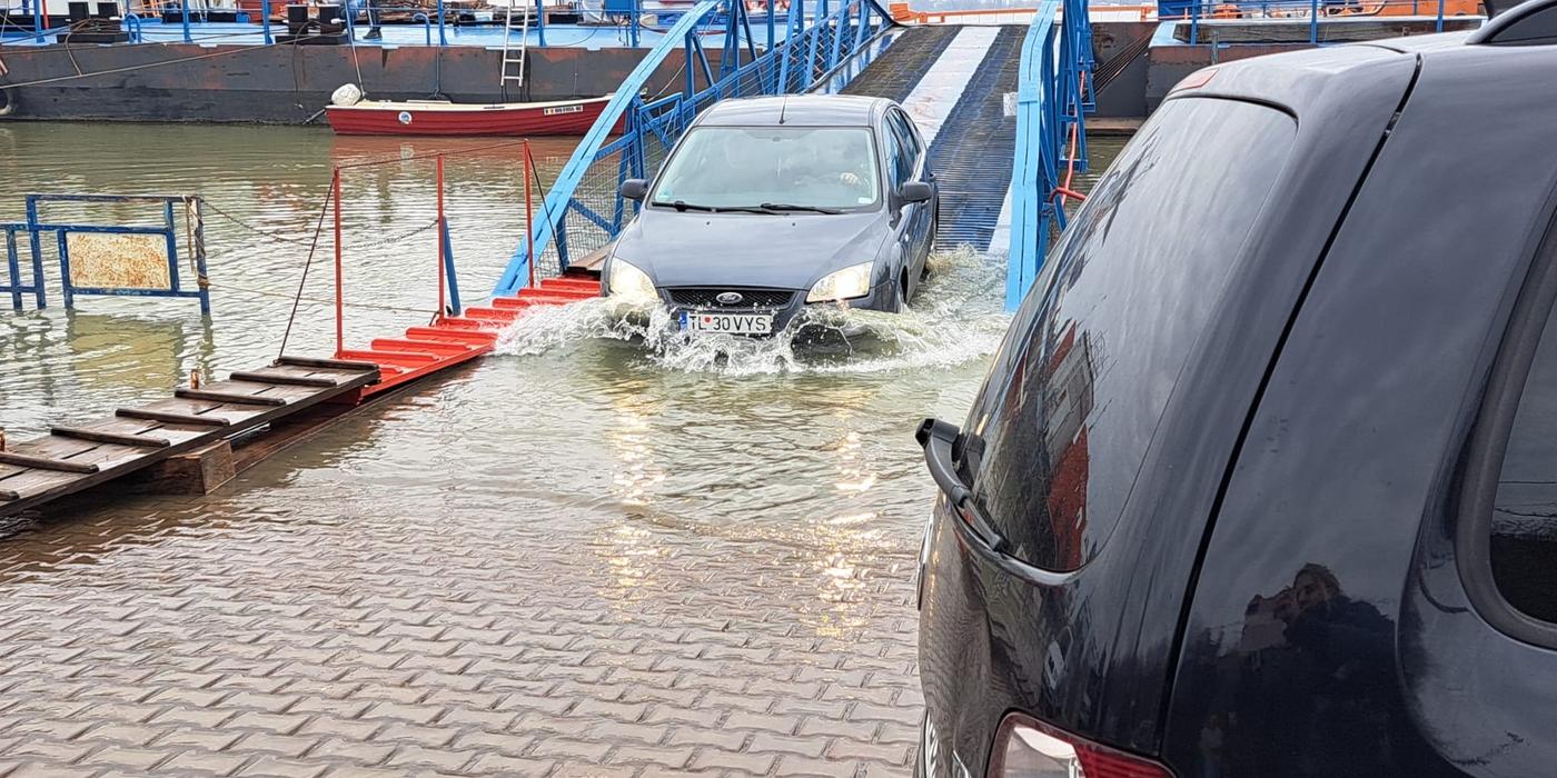 Maşinile trec prin apă ca să poată urca pe bacul de la Galaţi / Dunărea are debitul mult mai mare decât de obicei