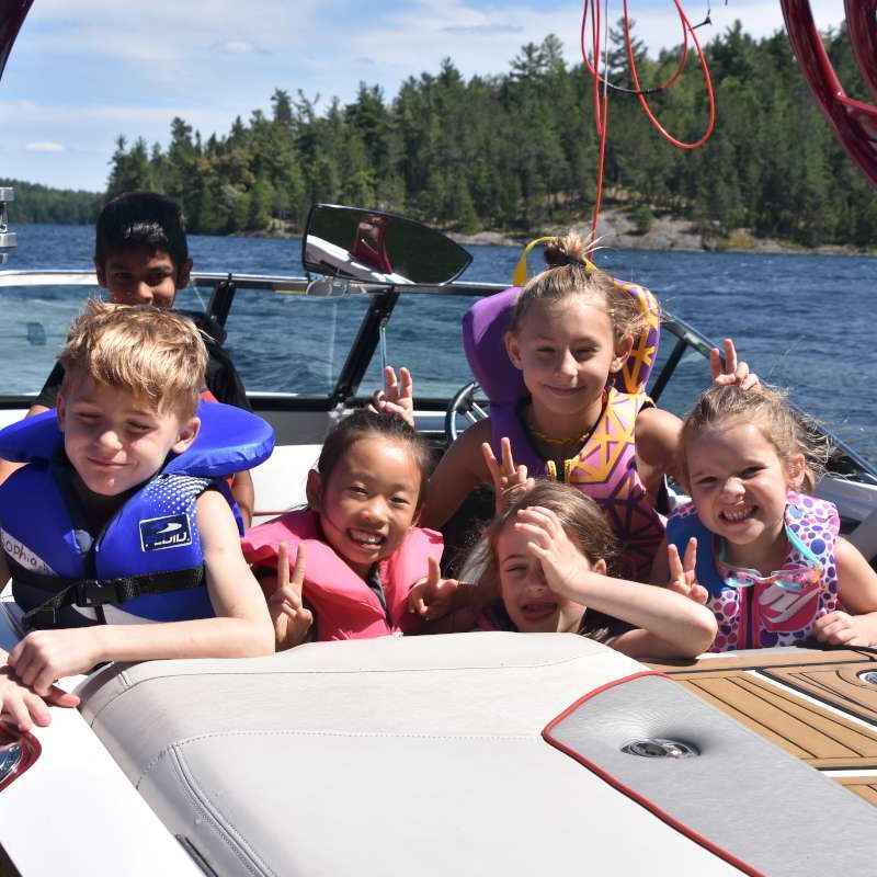 group of young campers on a boat smiling at the camera at Canadian Adventure Camp