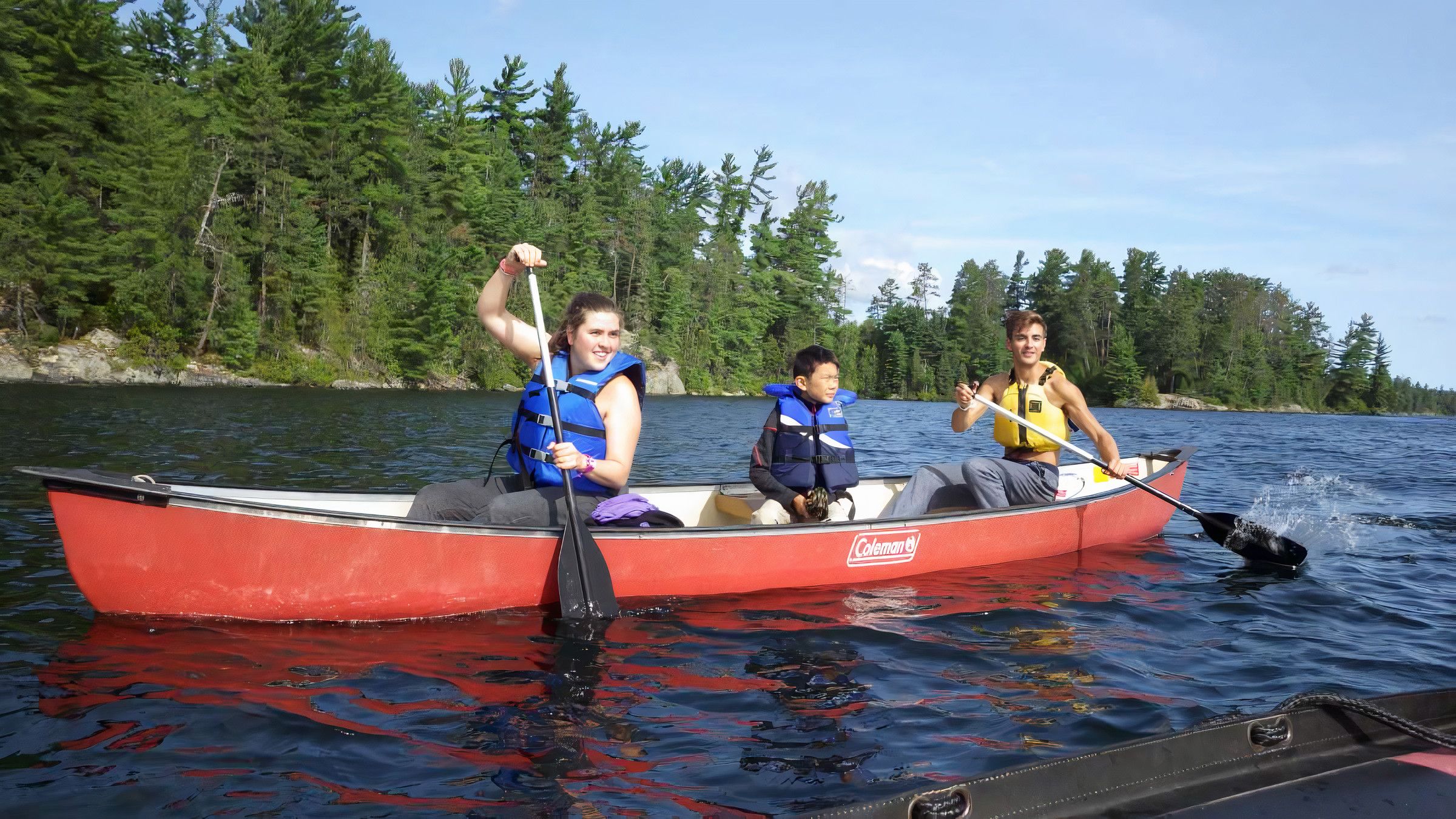 staff and camper canoeing and smiling at Canadian Adventure Camp