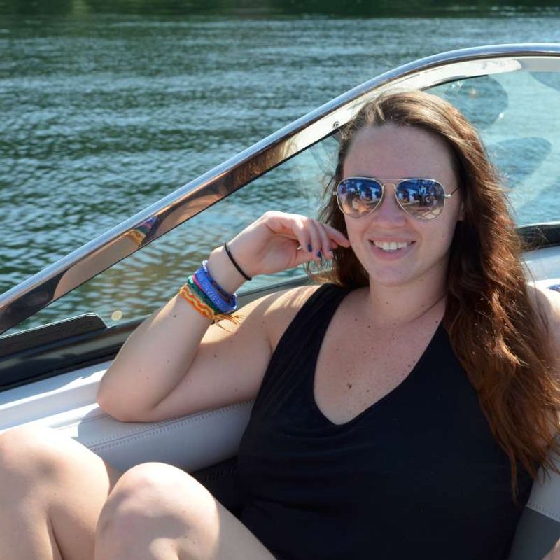 adult camper sitting in a boat, smiling at Canadian Adventure Camp