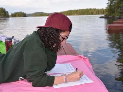 camper writing a letter on the dock at Canadian Adventure Camp