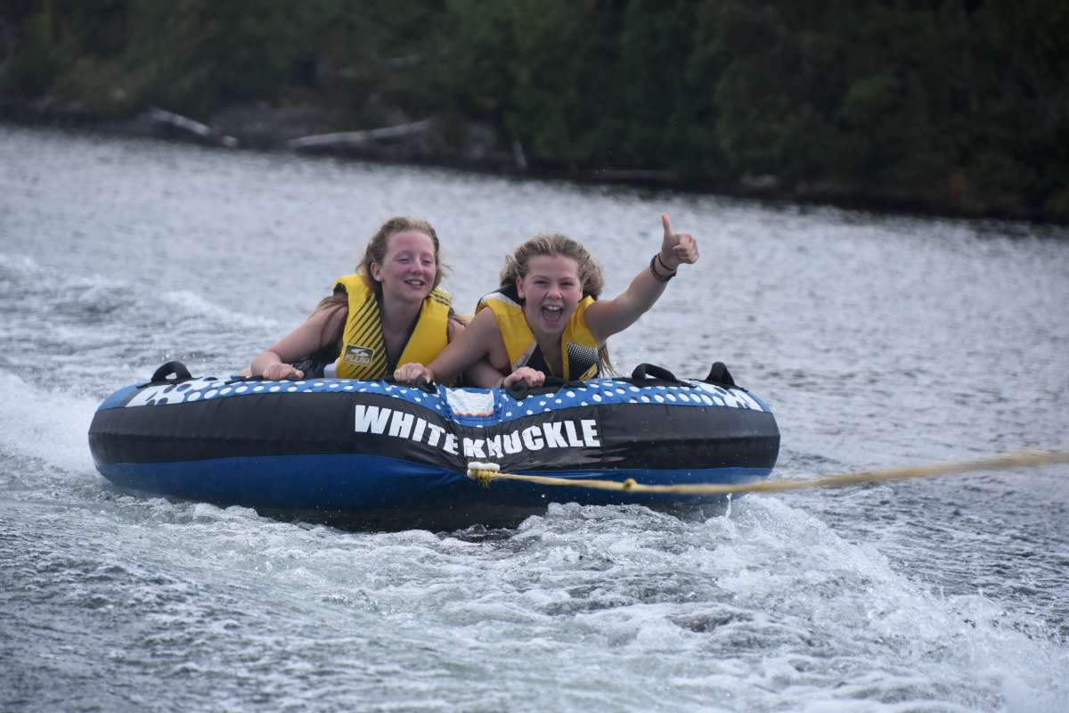 Two campers laughing while tubing on the lake at Canadian Adventure Camp