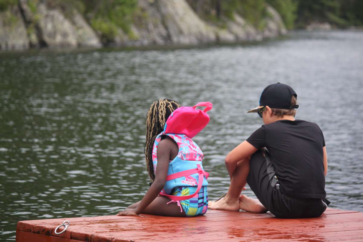 two younger campers sitting together on the dock