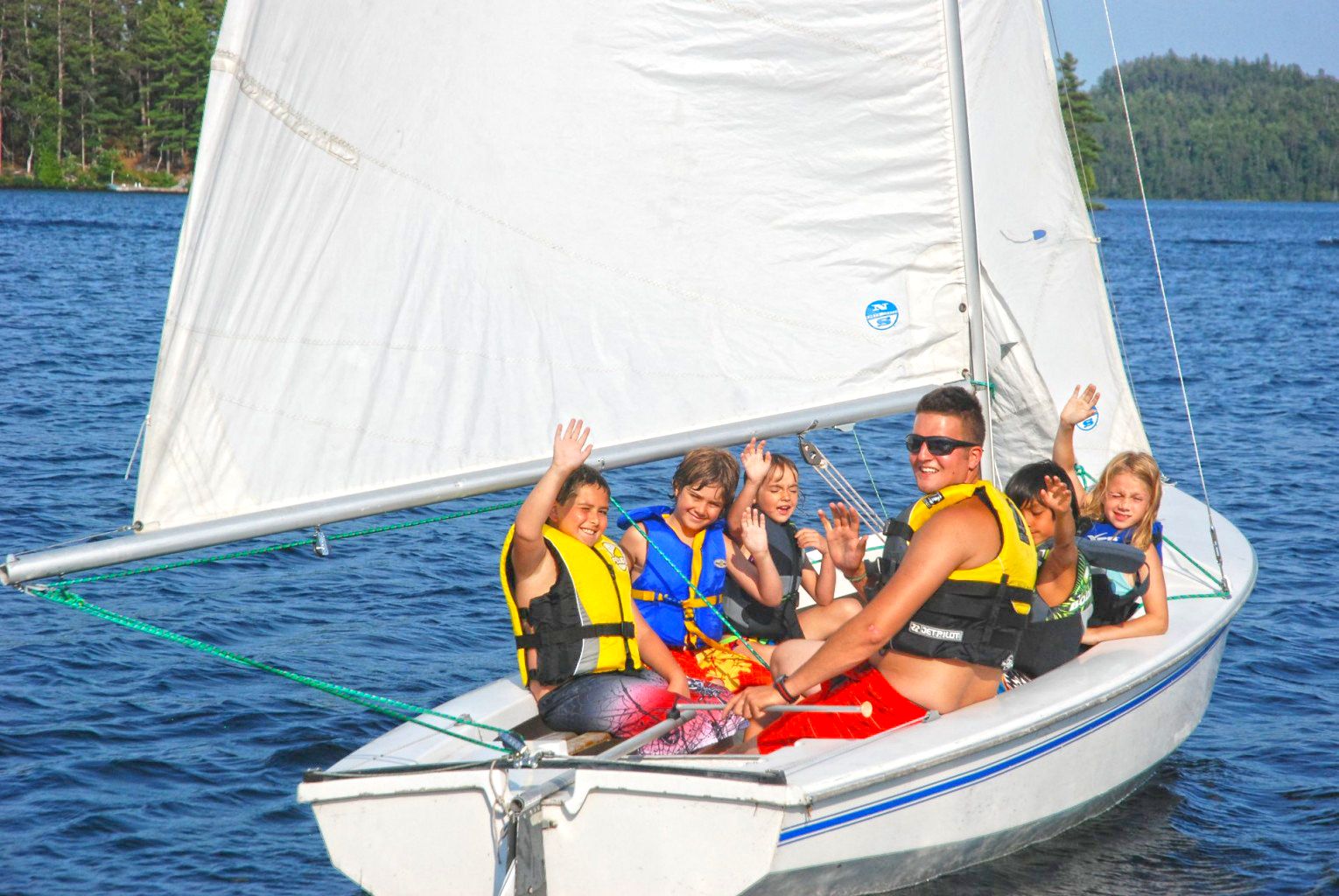 campers and counselor sailing on a boat