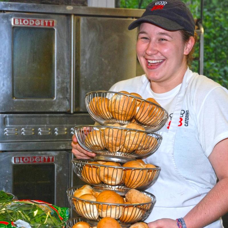 smiling kitchen staff carrying baskets of bread 