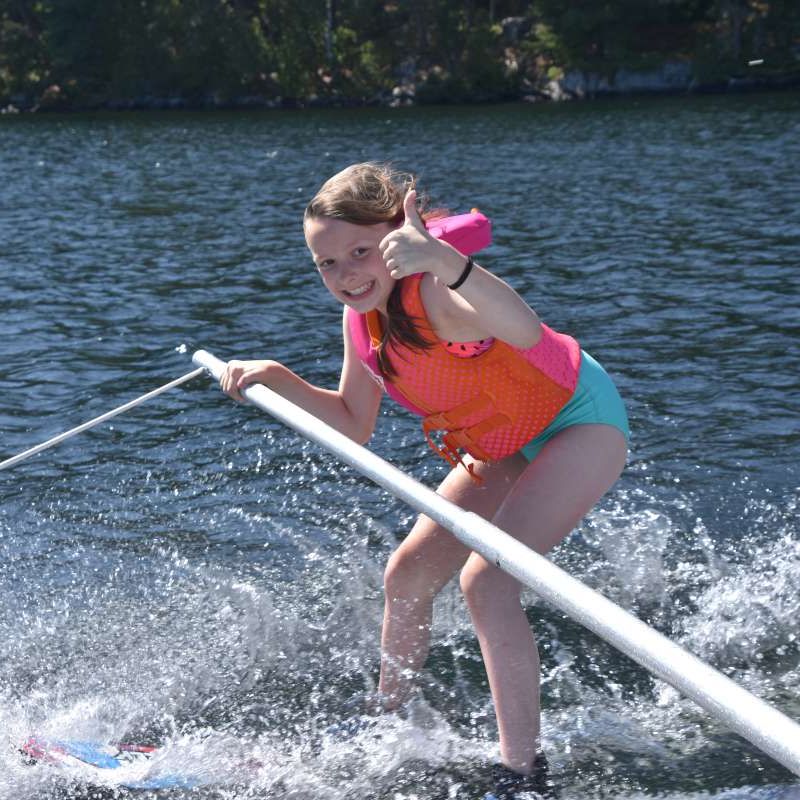 young camper with thumbs up waterskiing at Canadian Adventure Camp