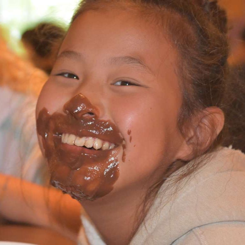 Dinnertime in the dining hall with campers eating pudding with their faces at Canadian Adventure Camp
