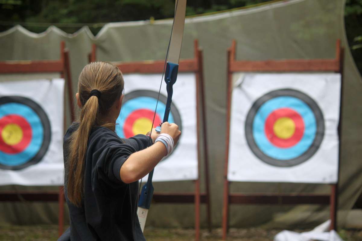 teenage camper at an archery session at camp