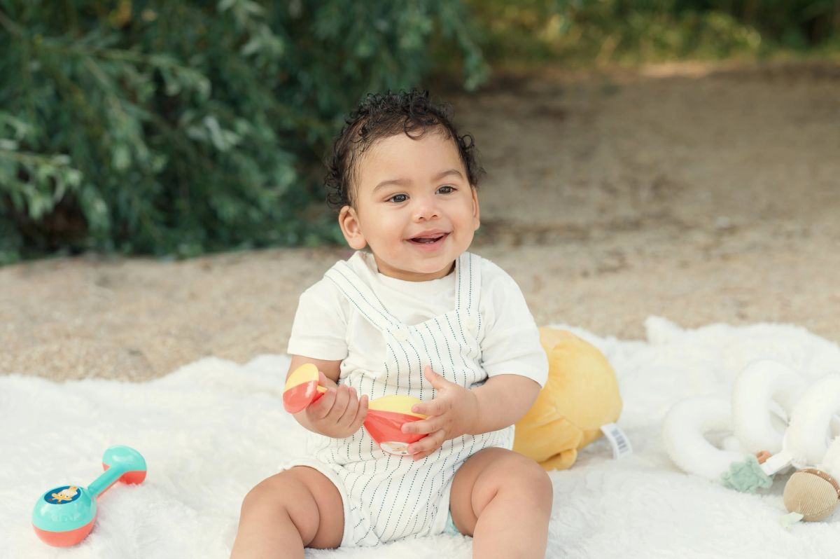 Bébé assis sur une couverture, entouré de ses jouets