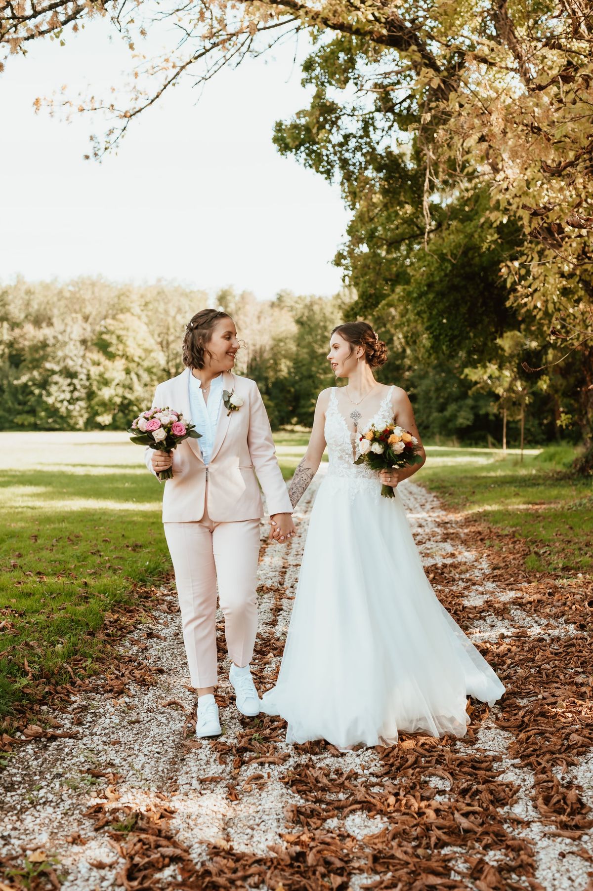 Deux mariées marchant main dans la main sur un chemin d’automne, mariage dans l’Aube