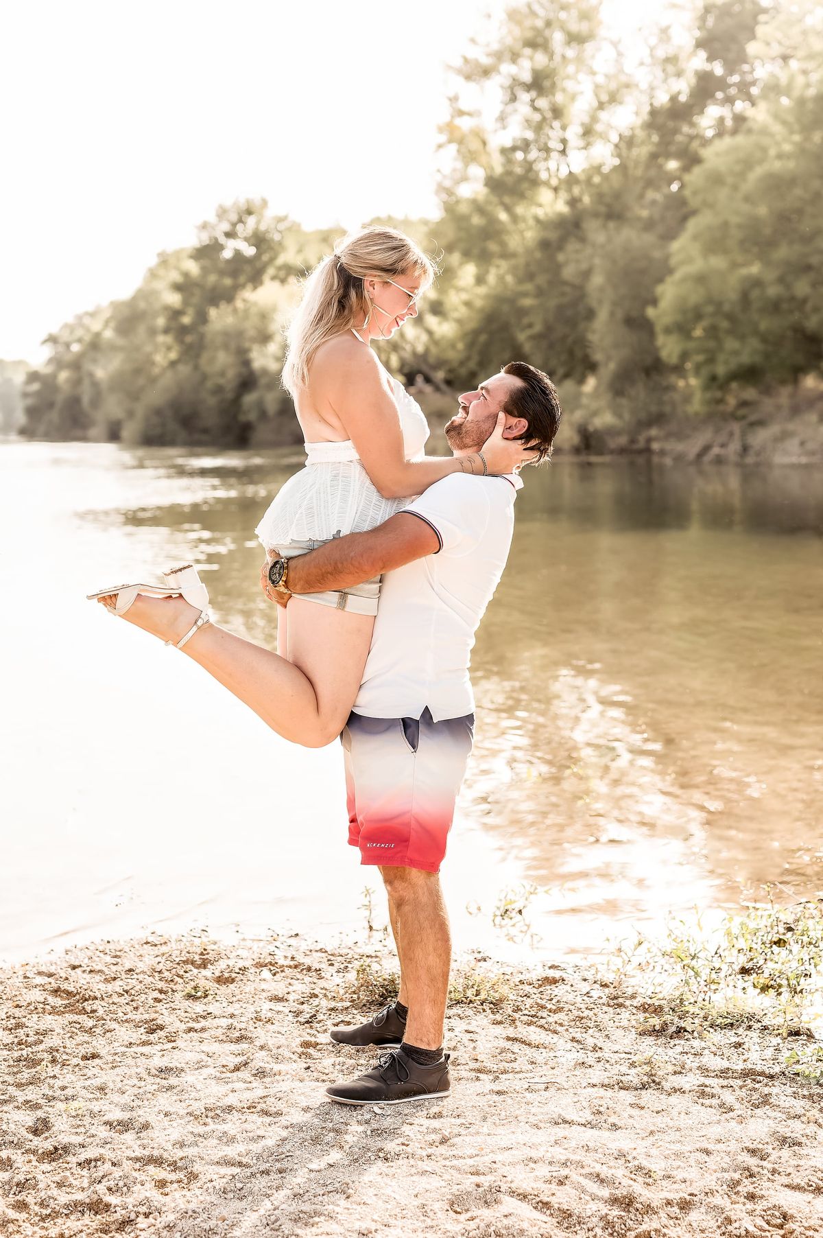 Couple complice au bord de l’eau, l’homme soulevant sa compagne