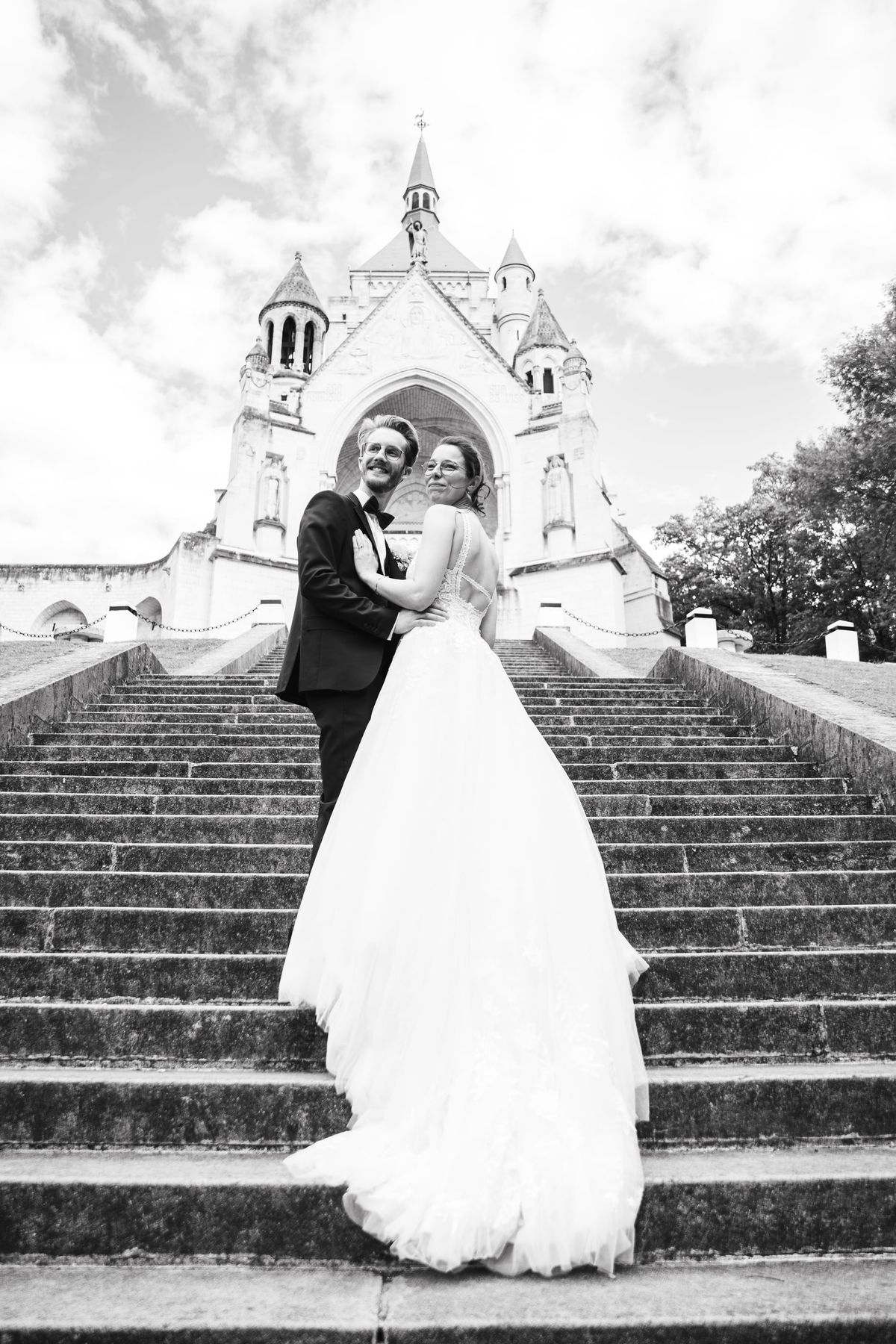 Mariés enlacés sur les marches d’une église, portrait en noir et blanc dans l’Aube