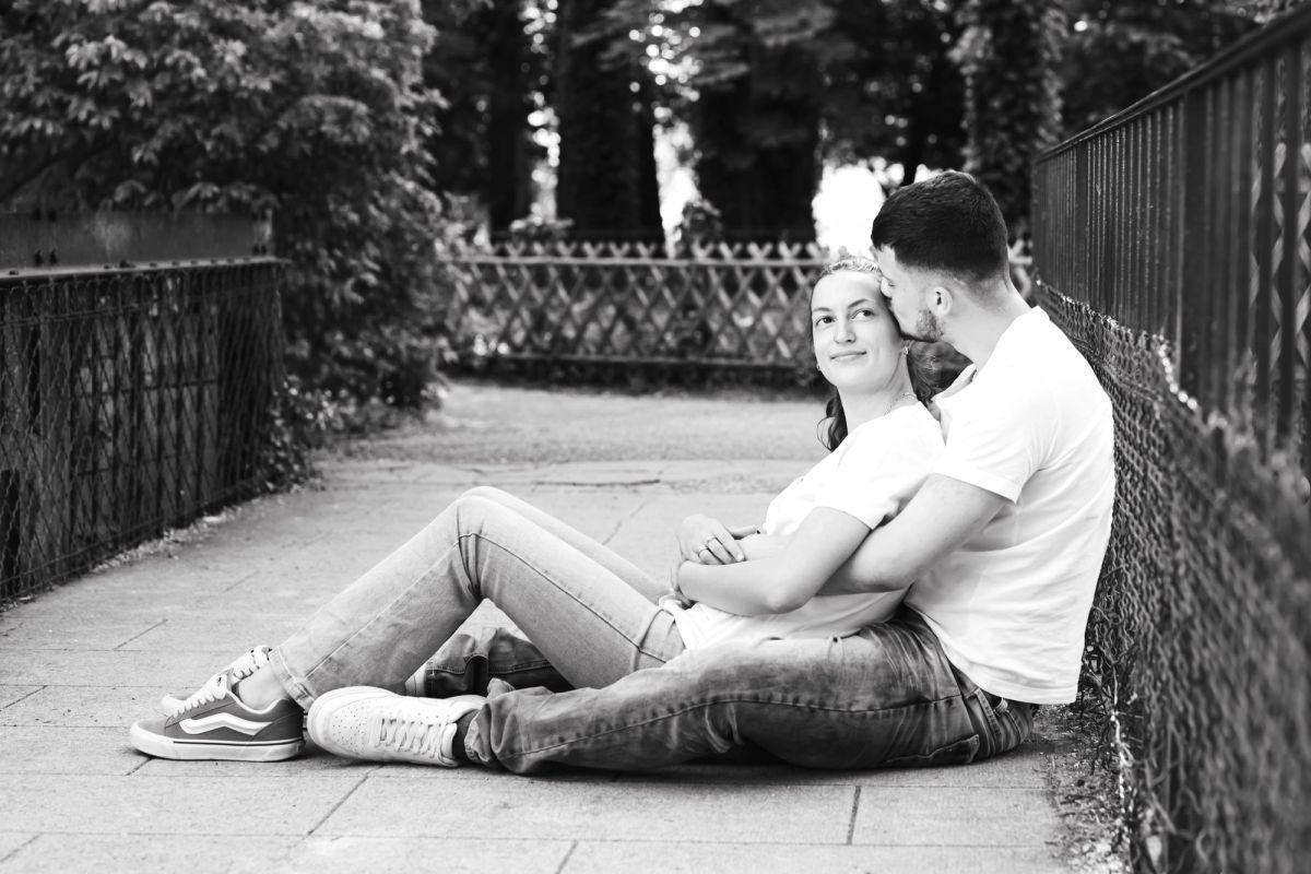Couple assis au sol dans une allée de parc, portrait en noir et blanc