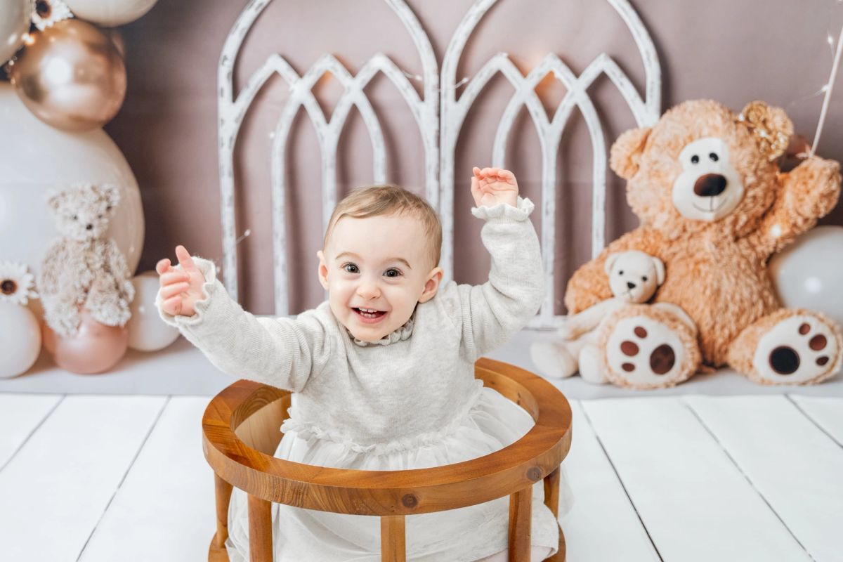 Bébé rieur dans sa chaise haute, entouré de peluches