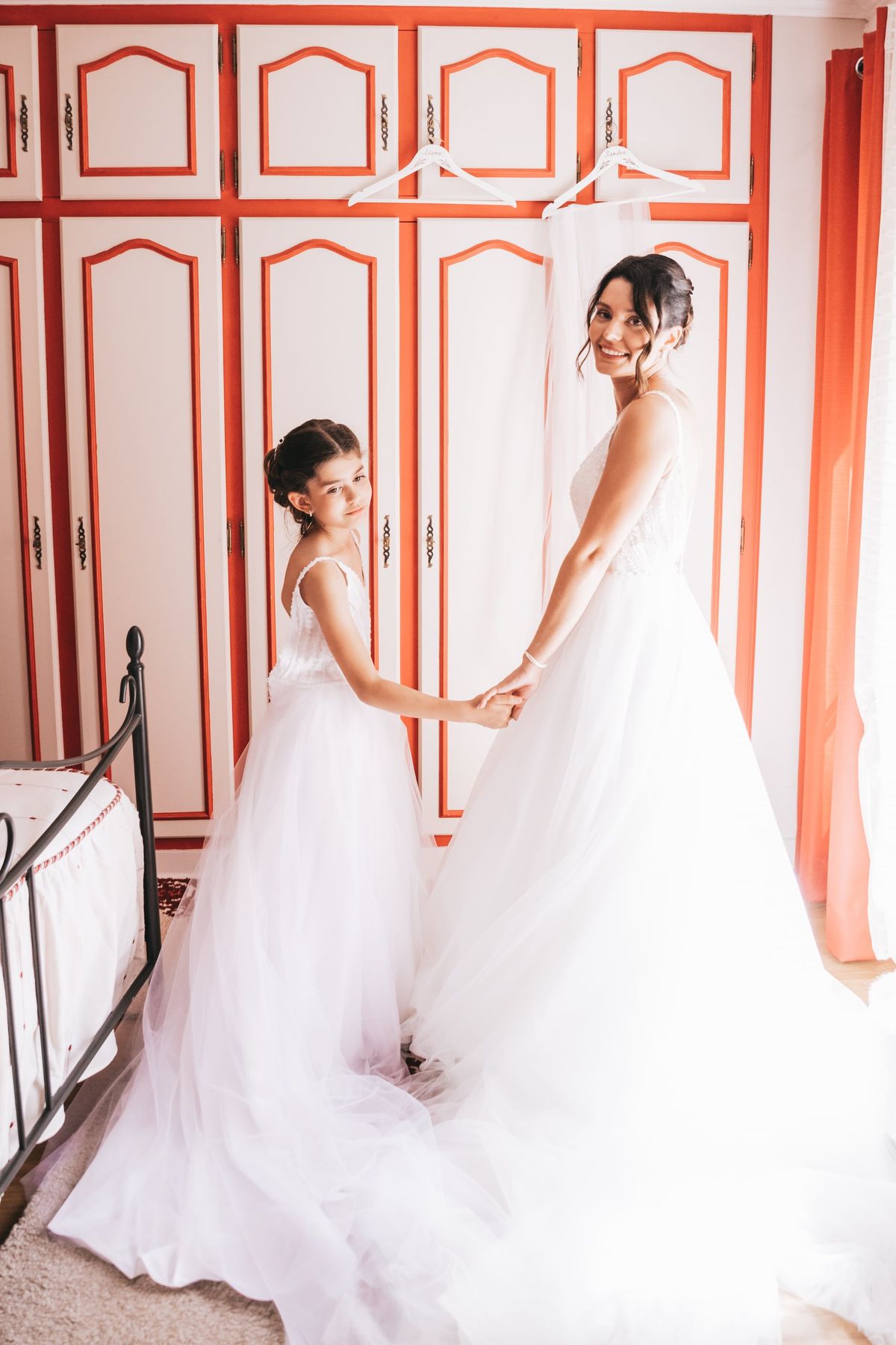 Deux mariées main dans la main en robe blanche, portrait en intérieur