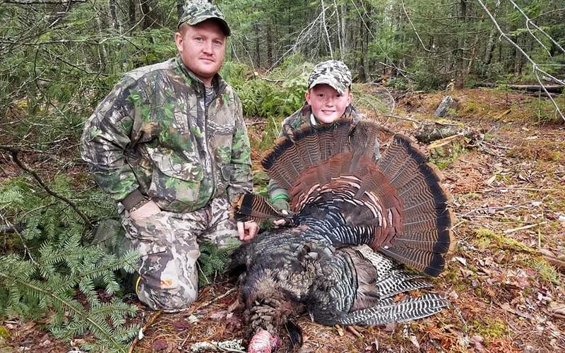 Young hunter and parent turkey hunting together in the spring woods