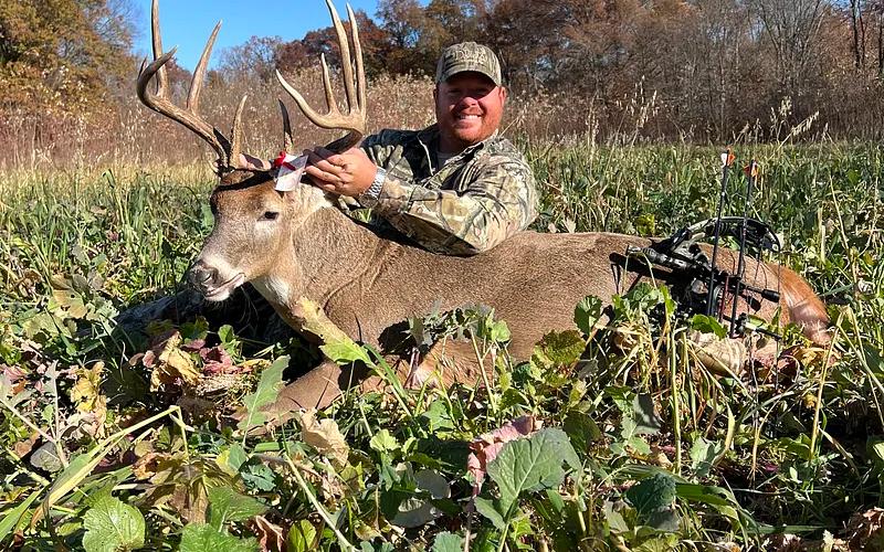 Hunter with a mature Illinois whitetail buck in Midwest farm country