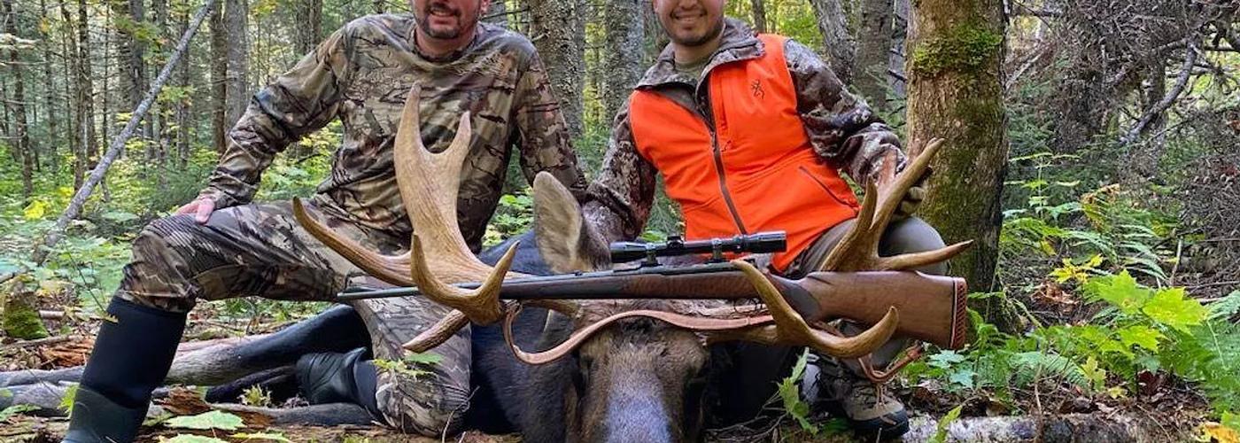 Bull moose standing near a remote Maine lake during a guided hunt.