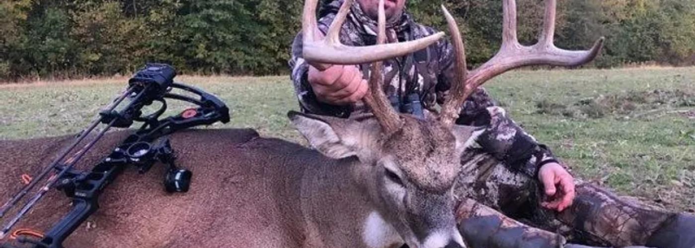 Mature whitetail buck standing in an Indiana hardwood forest during a guided deer hunt.