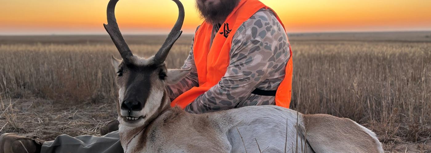 Hunter with pronghorn antelope buck in open Western prairie