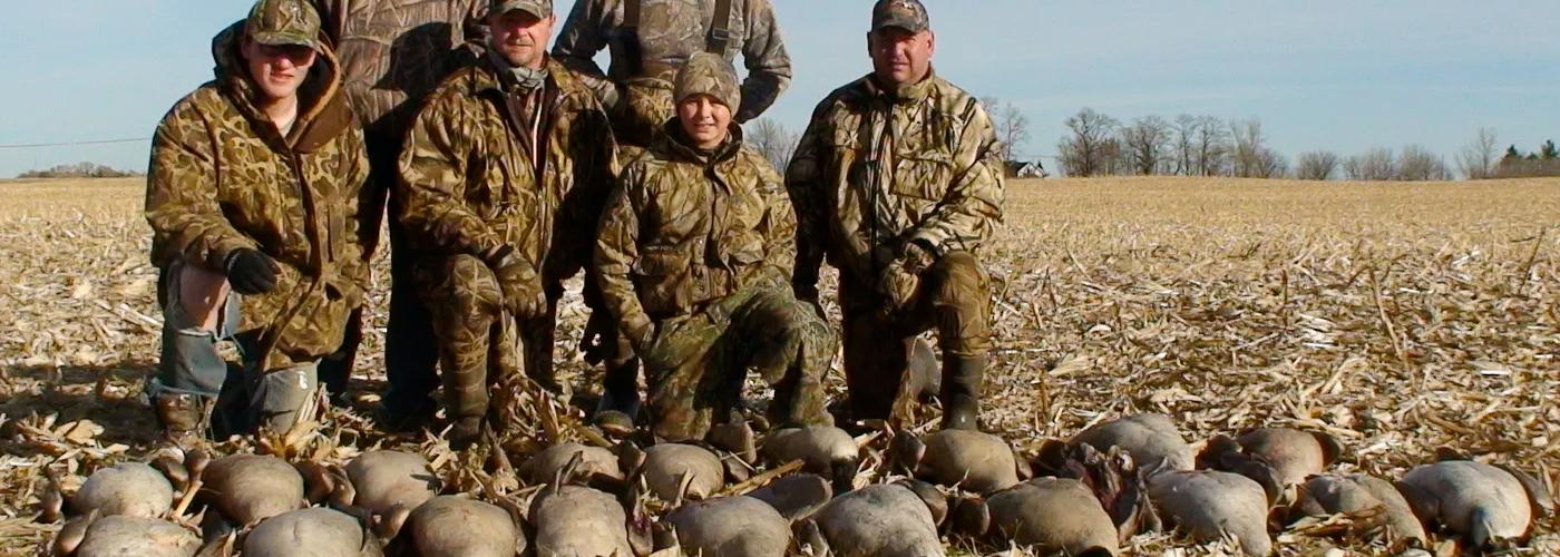 Hunters standing in a Minnesota field with mixed bag of goose and ducks.