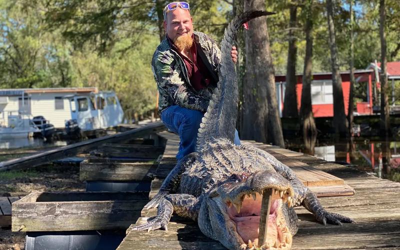 Hunter holding a harvested Louisiana alligator during a guided bayou hunt