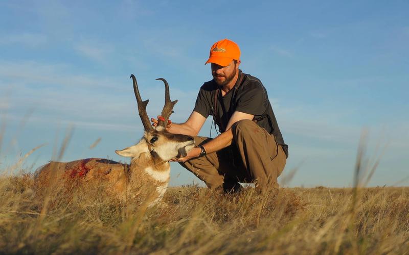 Hunter with a trophy pronghorn antelope buck on Wyoming prairie