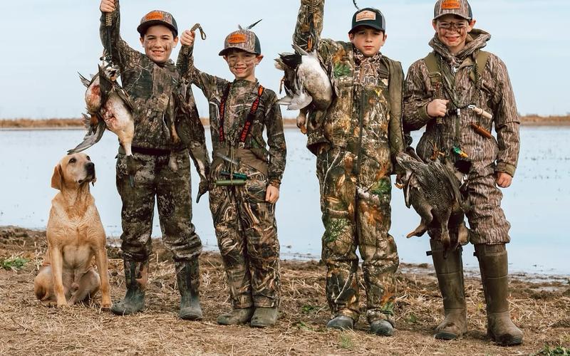 Parent and child duck hunting together from a blind