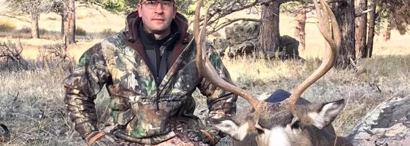Hunter with Mule Deer buck in Wyoming's rugged mountain country.