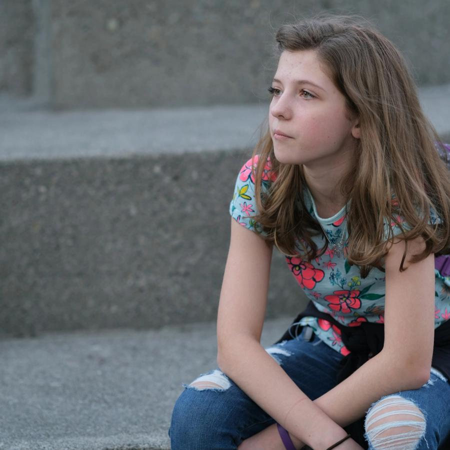 Ragazza seduta sui gradini con lo zaino, sguardo lontano