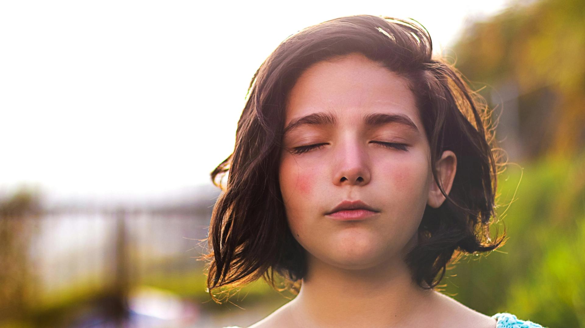 Ragazza a occhi chiusi al sole, serena