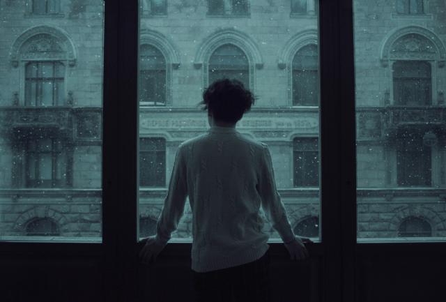 Persona di spalle davanti a una grande finestra, pensierosa