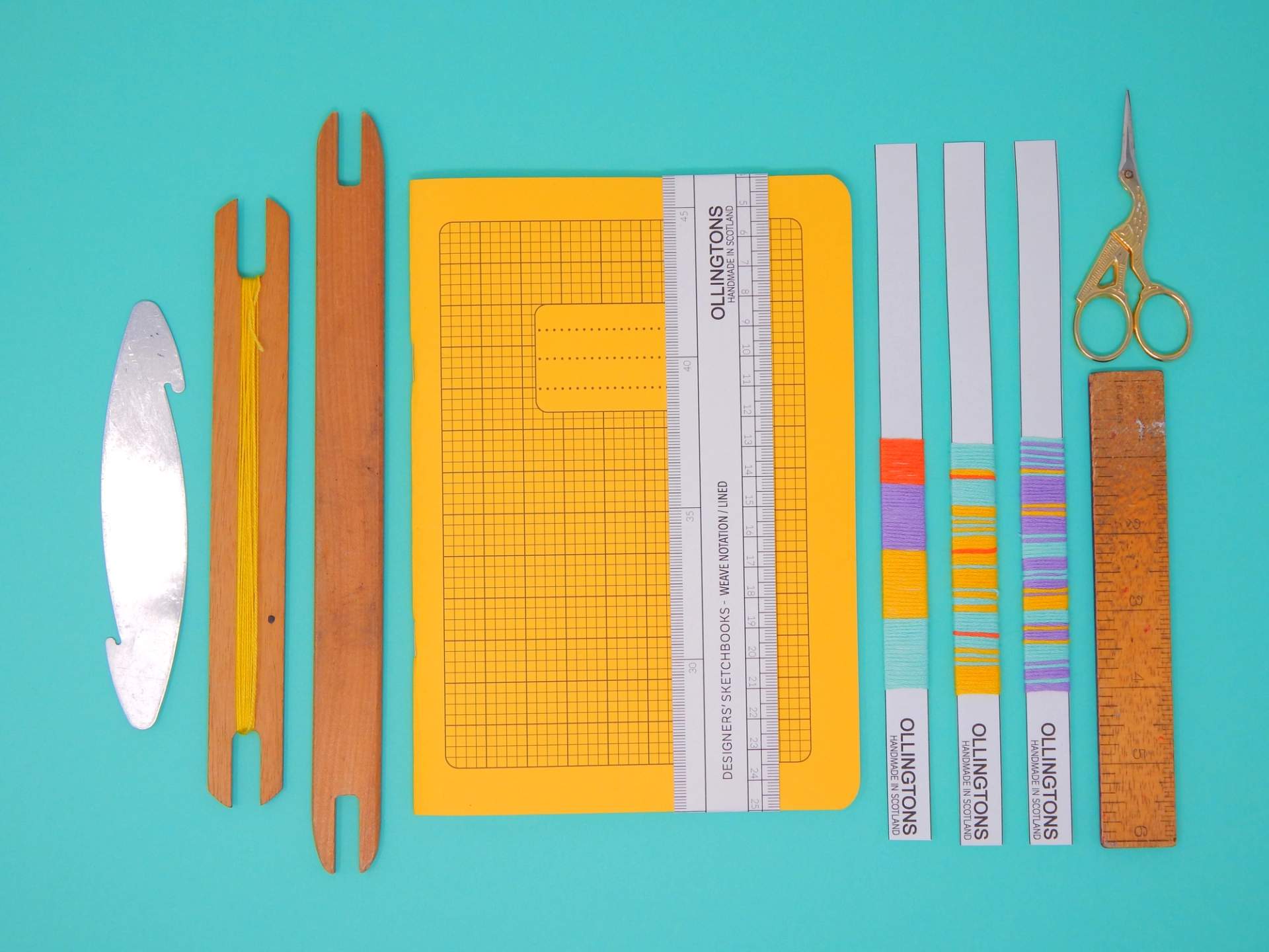 Ollingtons stationery flat lay with sketchbook, weaving tools, thread bookmarks, scissors and ruler