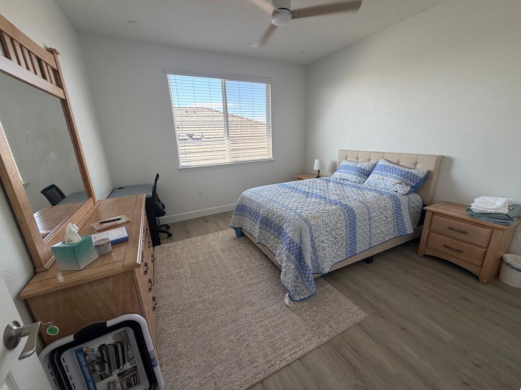 The available private bedroom, with a queen bed, a dresser and mirror, a desk, and a large window.