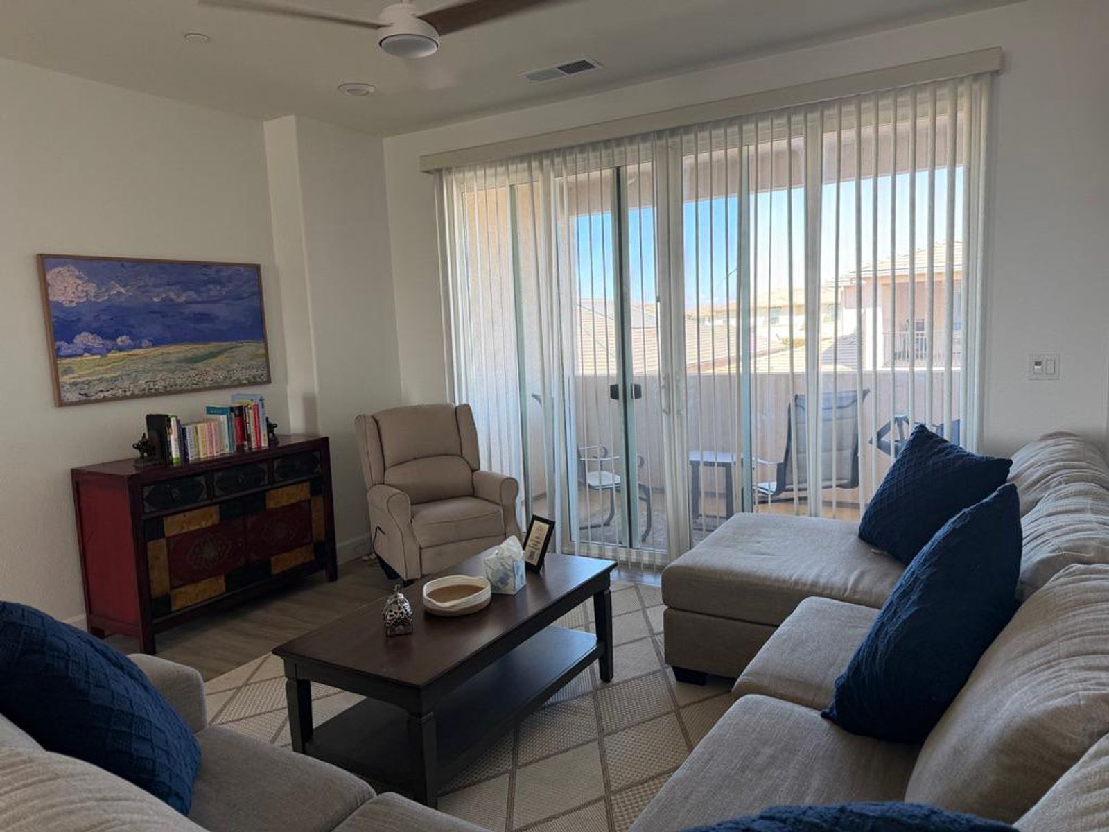 The upstairs family room at Maa Ghar, with a sectional sofa, a recliner, and a sliding door to the balcony.