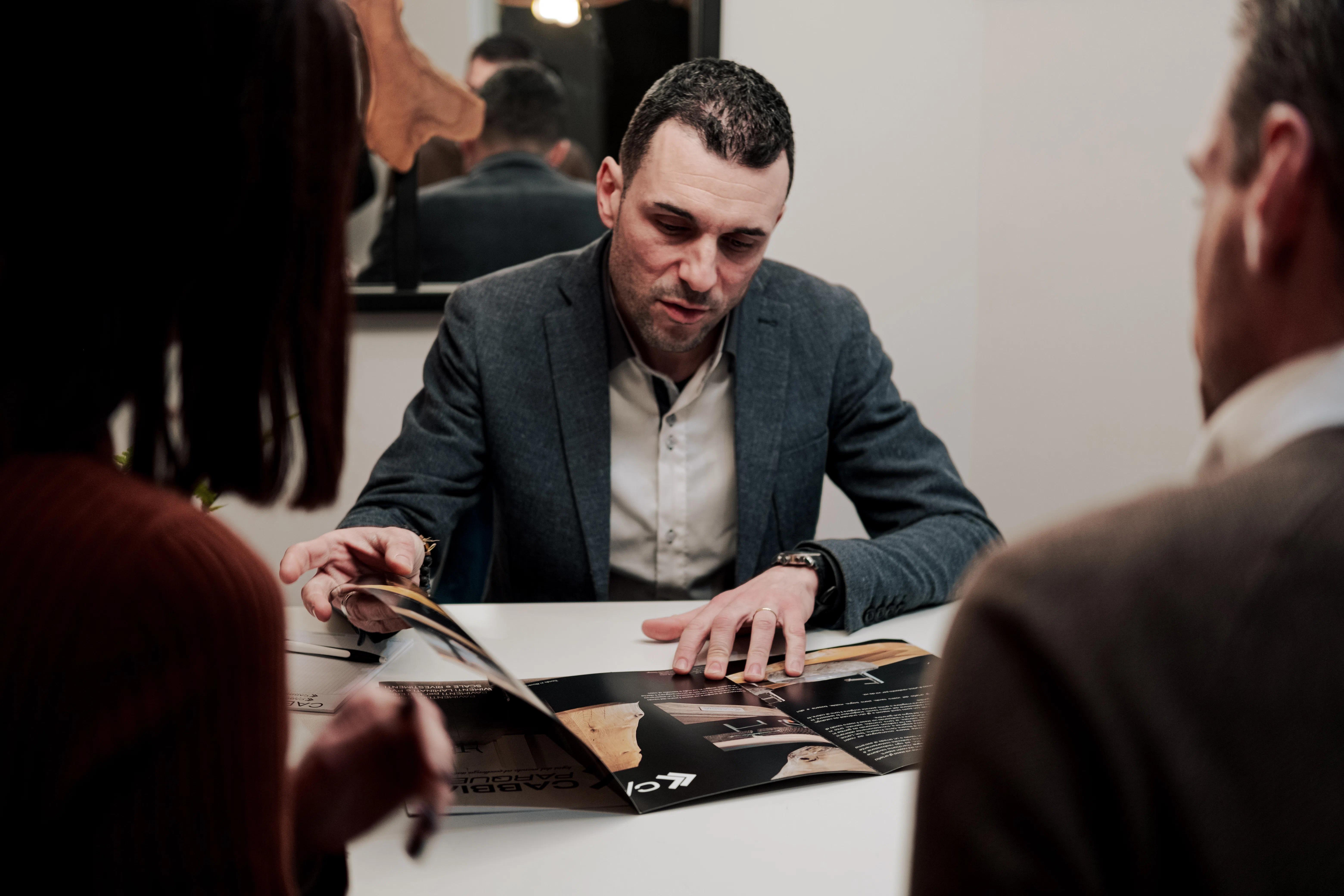 Consulente di Cabbia che mostra il catalogo a due clienti