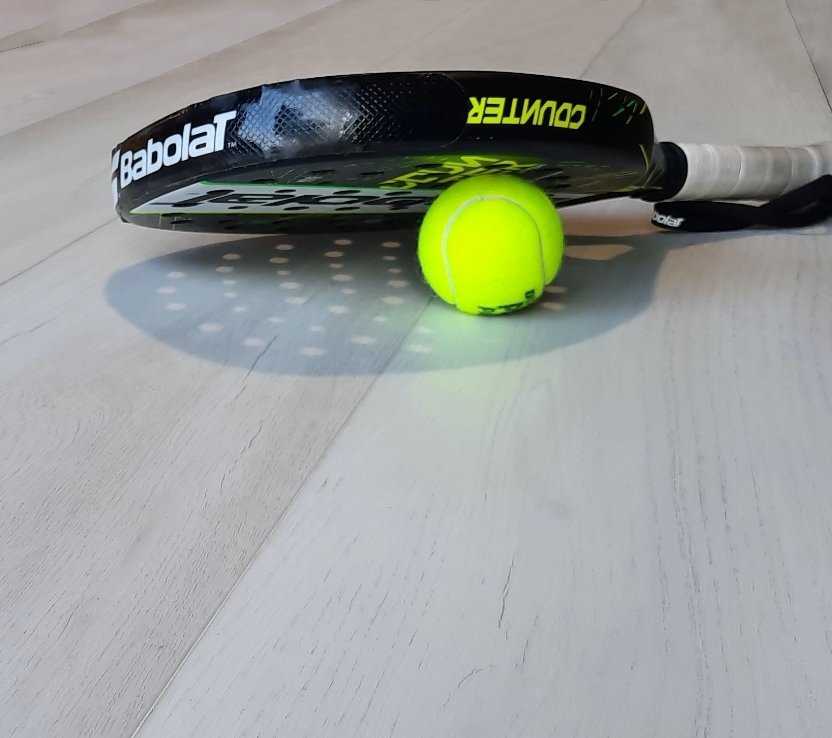 Racchetta e pallina da tennis su un parquet in legno Polar di Cabbia