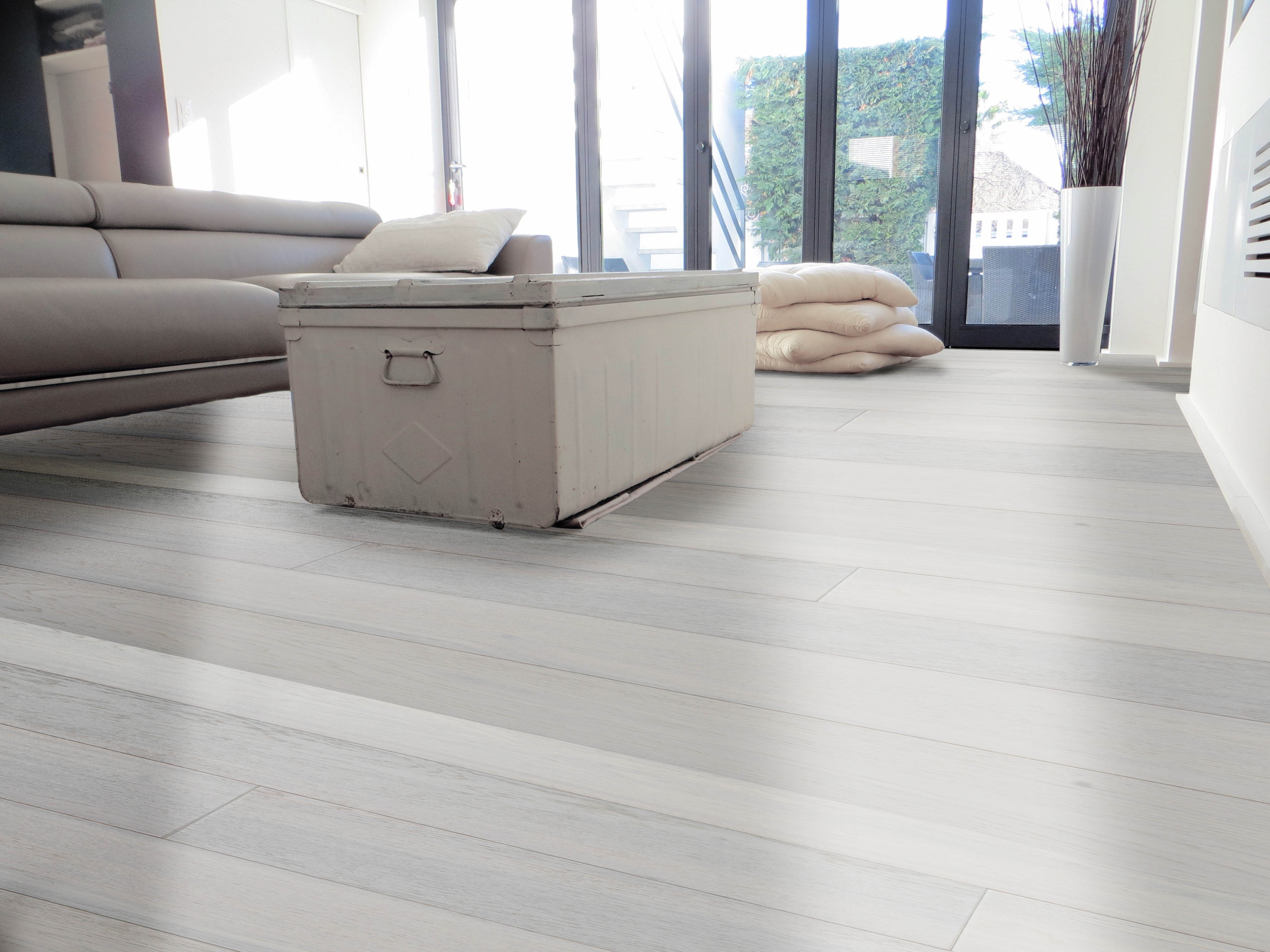 Divano e Pouf su un parquet Vogue Siberia Silver Grey di Cabbia con dettaglio floreale