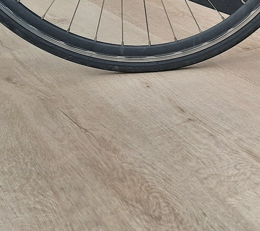 Ruota di una bicicletta su un parquet in legno Naturalizzato di Cabbia
