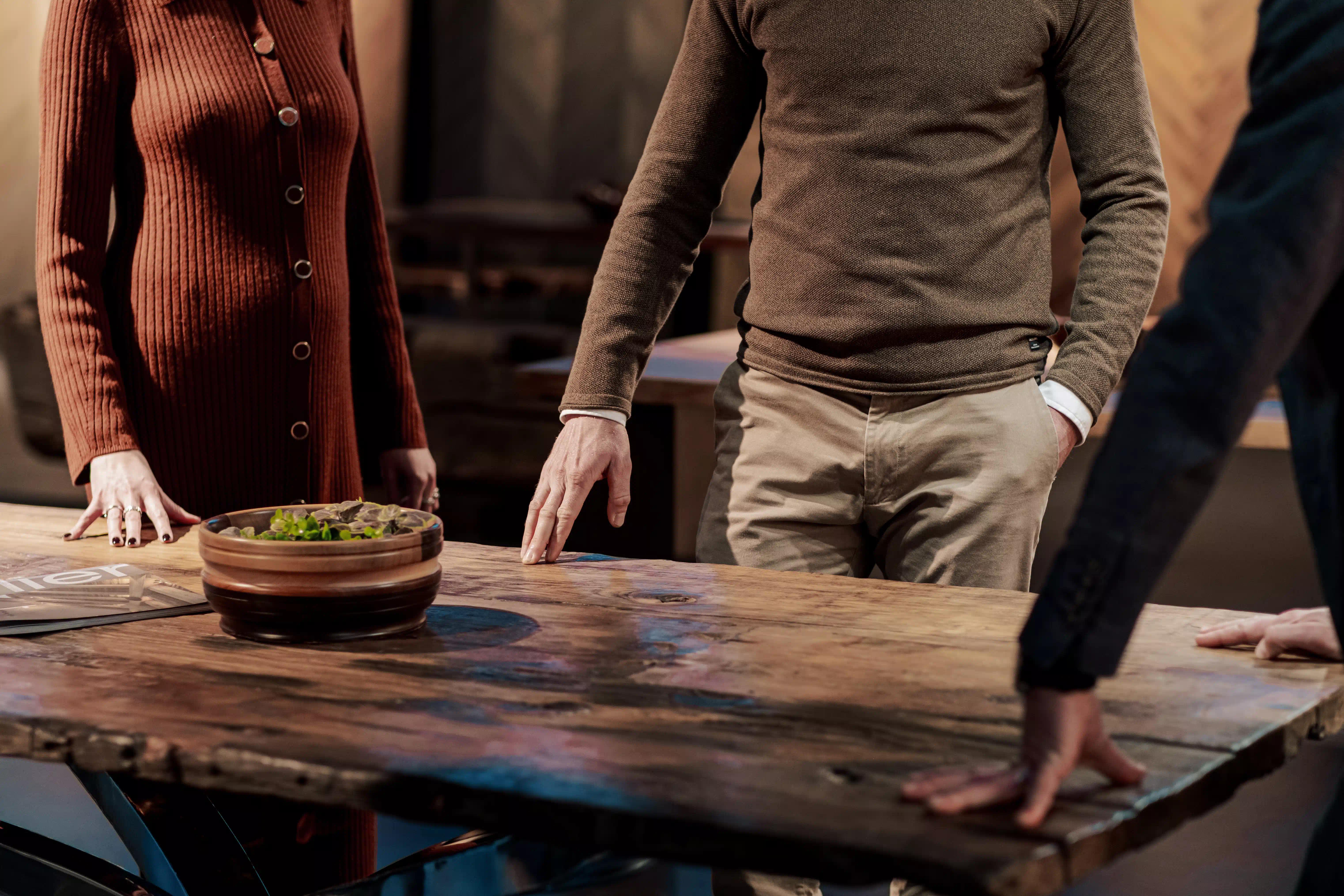 Consulente di Cabbia che mostra un tavolo in legno di Design a due clienti