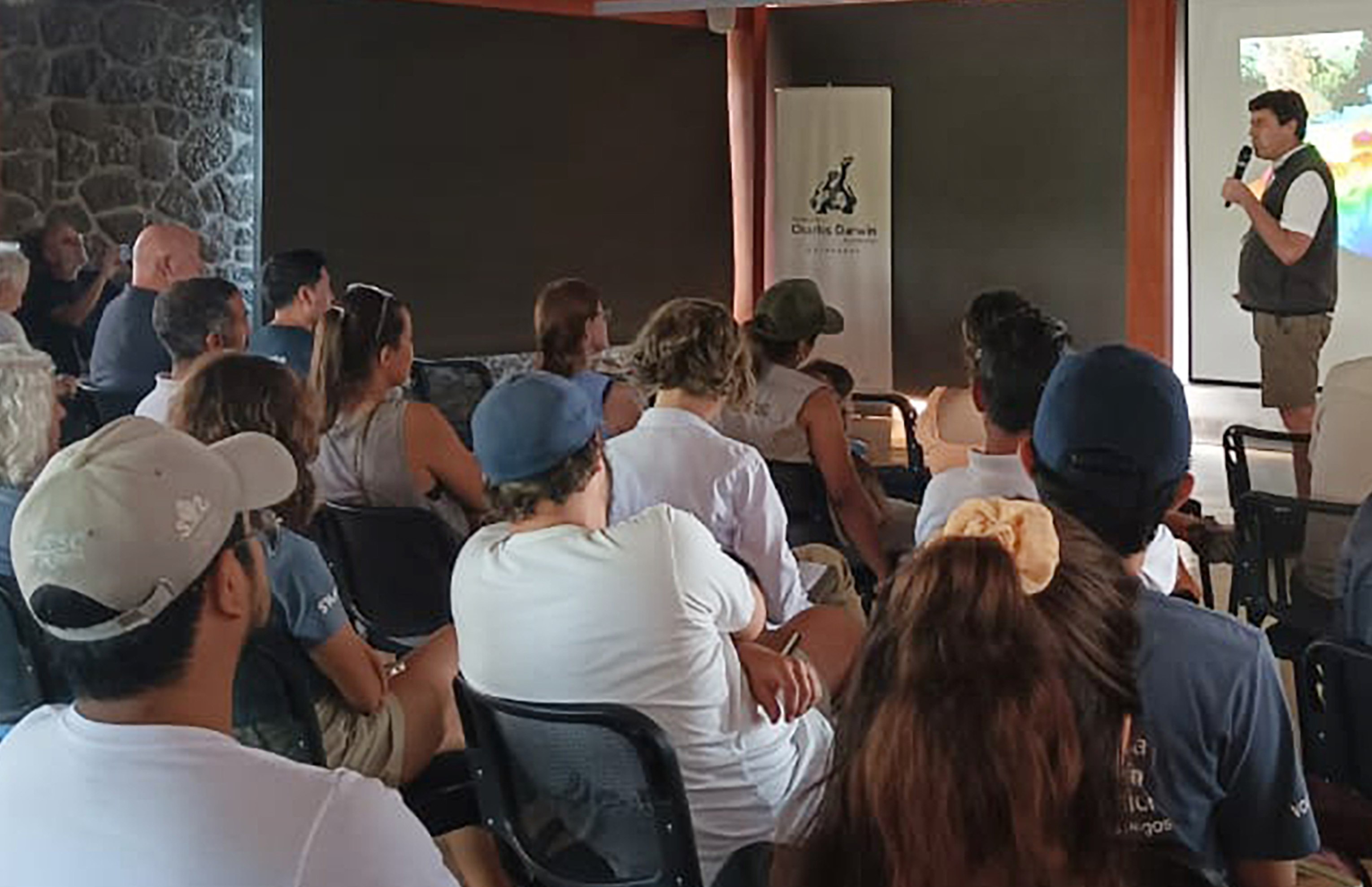 People speaking in front of a crowd while showing seafloor maps during a scientific talk