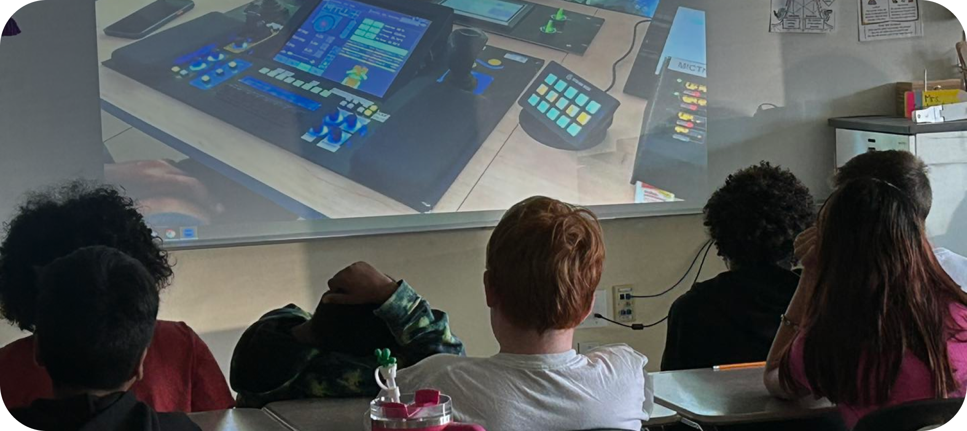 Five children are watching a projector screen of equipment.
