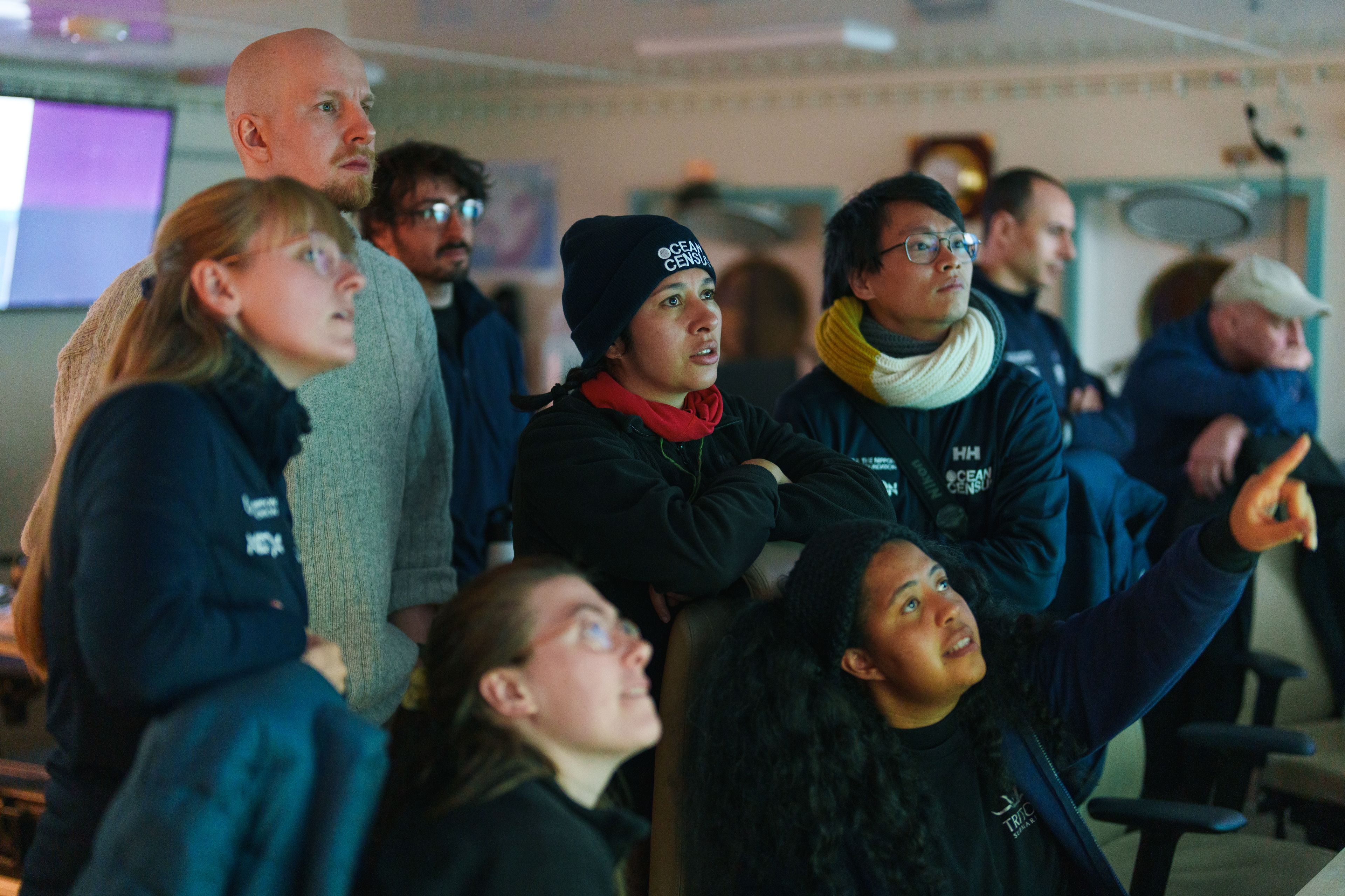 Researchers and crew reading mapping data on ship